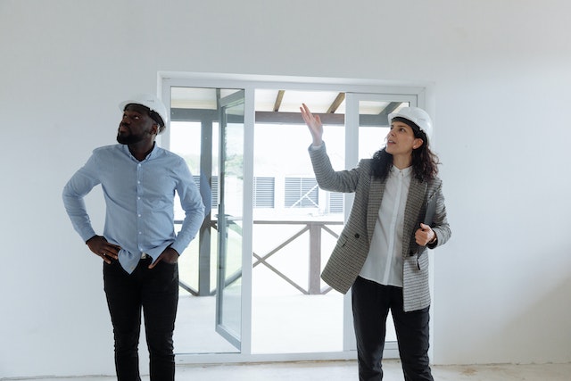 two property inspectors in white hardhats looking at an unfurnished room